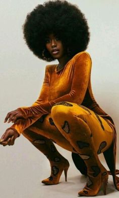 a woman with an afro sitting on top of a chair wearing yellow leggings