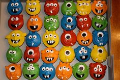 a box filled with lots of different colored cupcakes covered in monster faces on top of each other