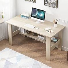 a desk with a computer on top of it in front of a white wall and wooden floor