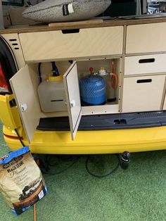 a yellow car with its doors open on the ground next to other vehicles and tools