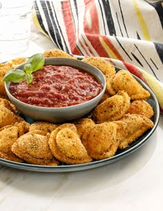 a platter filled with deep fried ravioli and dipping sauce