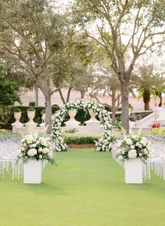 an outdoor ceremony setup with white flowers and greenery