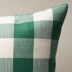 a green and white checkered pillow sitting on top of a couch next to a wall