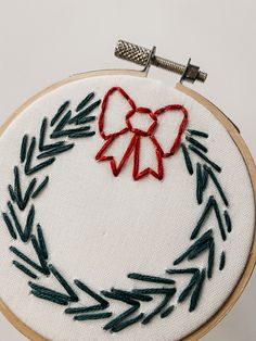 an embroidered wreath with a red bow on it