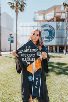 a woman in graduation gown holding up a sign that says i'm graduating you can't be beautiful