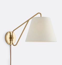 a wall lamp with a white shade on it's side and a gold arm