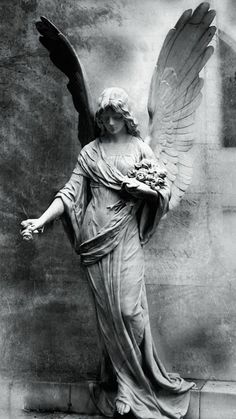 an angel statue with outstretched wings holding a bouquet of flowers in front of a wall