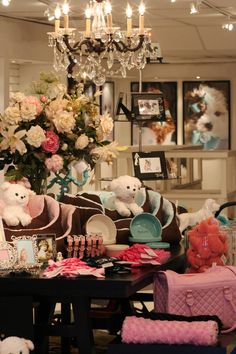 a room filled with lots of stuffed animals next to a table and chandelier