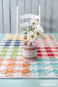 a vase with daisies in it sitting on top of a checkered table cloth