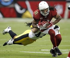 a football player diving for the ball while being tackled by another player in a game