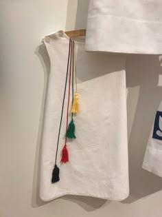 a white towel hanging from a wooden hanger with tassels attached to it