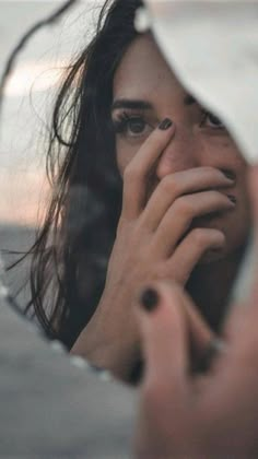 a woman holding her face in front of a mirror