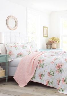 a white bed with pink flowers on it and a light blue nightstand next to it