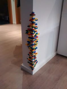 a tall building made out of legos on the floor next to a white wall