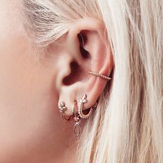 a woman with blonde hair wearing gold ear cuffs and piercings on her left ear