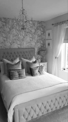 black and white photograph of a bedroom with stone walls, bedding, and chandelier