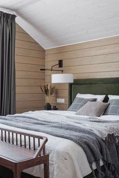 a bedroom with wood paneled walls and white bedding, along with a green headboard