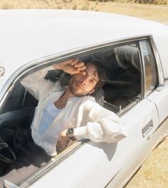 a man sitting in the driver's seat of a car with his hand on his head