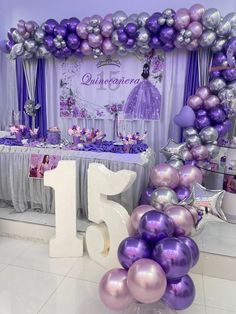 purple and silver balloons are on display in front of a table with the number fifteen