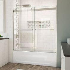 a bathroom with white tile and wood flooring, including a walk - in shower