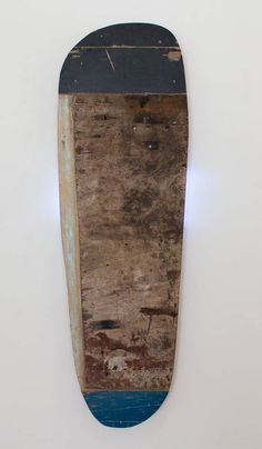 an old skateboard is hanging on the wall in front of a white wall with peeling paint