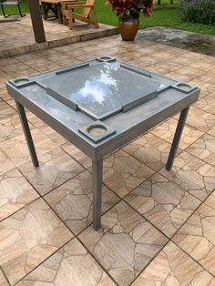 a glass table sitting on top of a stone floor next to a potted plant