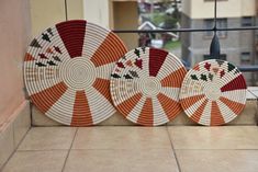 three orange and white plates sitting next to each other on a tile floor near a window