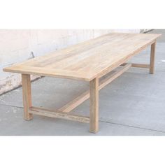 a wooden table sitting on top of a cement floor next to a white brick wall