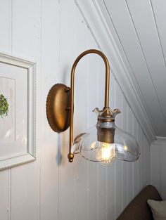 an old fashioned brass wall light on the side of a white painted room with wood paneling