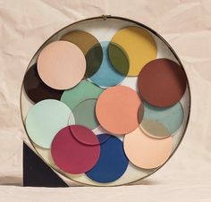 a bowl filled with different colored discs on top of a white table next to a brown wall