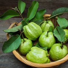 a wicker basket filled with green pears and leaves