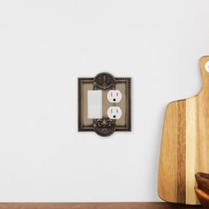 a wooden cutting board sitting next to a light switch