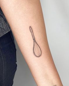 a woman's arm with a tattoo on it that has a whisk in it