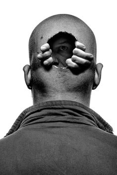 a black and white photo of a man's face with hands covering his eyes