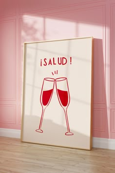 two glasses of wine are in front of a framed poster that says i salud