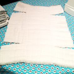 an unmade bed with blue and white bedspread on it's edge