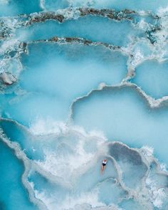 an aerial view of a man swimming in the blue water at mammoth springs, yellowstone national park