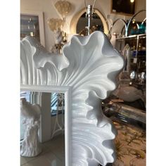 a large white mirror sitting on top of a table next to a wall mounted light