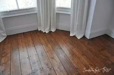 an empty room with wooden floors and white curtains