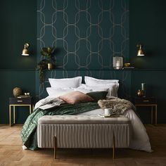 a bedroom with green walls, white bedding and gold accents on the headboard