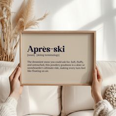 a person holding up a sign that says apres - ski in front of a white couch