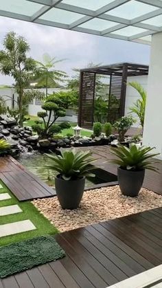 an outdoor area with plants and rocks in the center, grass on the ground and wooden decking