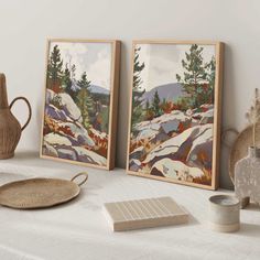 two framed pictures sitting on top of a table next to vases and other items