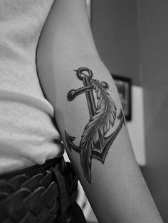 a black and white photo of a woman's arm with an anchor tattoo