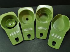 four green measuring cups sitting next to each other on a black counter top with labels