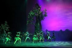 a group of people that are on stage in front of a tree and some lights