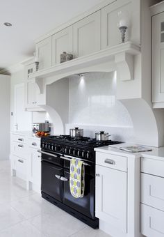 a kitchen with white cabinets and an oven in the center is seen from across the room