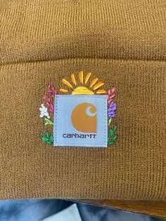 a brown beanie hat with the word campbell on it and an image of sunflowers