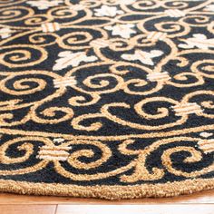 a black and gold rug on the floor with wood floors in the background, close up