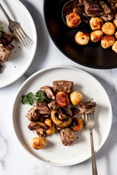 two white plates topped with meat and vegetables next to a fork on a marble counter